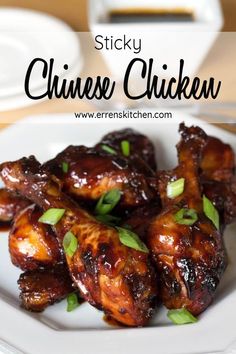 a white plate topped with chicken wings covered in sauce and garnished with green leaves