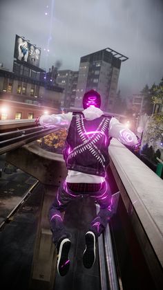 a man sitting on top of a metal rail next to a train track in front of tall buildings