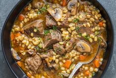 a black bowl filled with stew and vegetables