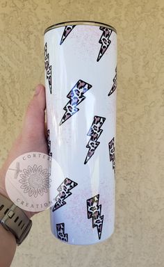 a hand holding a white coffee cup with black and pink designs on it's side