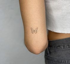 a woman's arm with a small butterfly tattoo on the left side of her arm