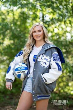 a beautiful young woman holding a volleyball ball in her right hand and posing for the camera