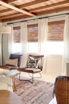 a living room filled with furniture and windows covered in shades of white draping