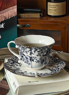 a tea cup and saucer sitting on top of a stack of books