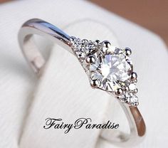 a diamond ring is sitting on top of a white cloth with the words fairy paradise written below it