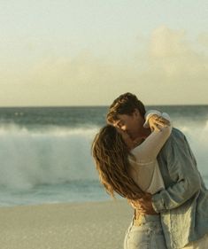 a man and woman embracing on the beach