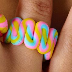 a woman's hand holding a ring with multicolored swirls on it