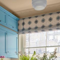 a kitchen window with blue cabinets and potted plants