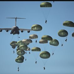 an airplane is flying in the sky with parachutes