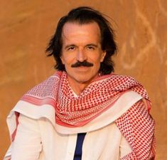 a man with long hair and a mustache wearing a red and white scarf around his neck