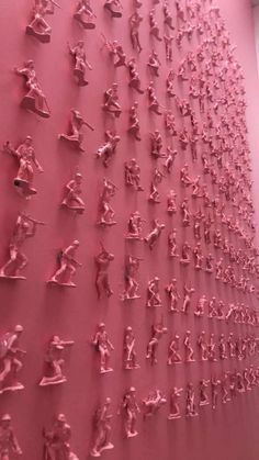 a pink wall with many small figures on it