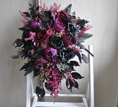 a purple and black bouquet sitting on top of a white chair next to a wall