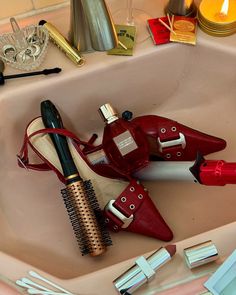 a pair of red high heeled shoes sitting on top of a sink next to a brush