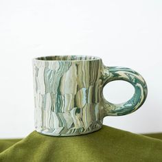 a coffee cup sitting on top of a green cloth