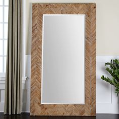 a mirror sitting on top of a wooden floor next to a potted green plant