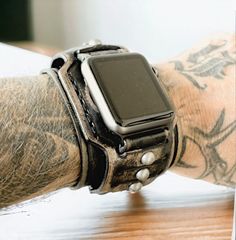 Check out this awesome vintage-looking distressed black leather cuff made for your Apple Watch! It's rugged, with antique silver rivets and made from high-quality full-grain leather. The 2-inch wide band is handcrafted in the USA, ensuring the best quality for your wrist! Each item is handmade and designed by Cuckoo Nest Art Studio™. The watch bands made from vegetable tanned leather what is known as the highest quality leather available and used for high-end handmade leather goods. Usually, this kind of leather is stiff in the beginning however, it does get wonderfully soft and pliant over time. Vegetable tanned leather provides great value for money due to its durability and never goes out of style. MADE IN USA CUCKOO NEST ART STUDIO™ DESIGN  This listing is for the WATCH STRAP BAND + co Vintage Leather Apple Watch Band With Bracelet Strap, Vintage Leather Bracelet Strap For Apple Watch, Vintage Silver Leather Watch Accessories, Vintage Black Adjustable Watch Bands, Vintage Adjustable Bracelet Strap Apple Watch Band, Adjustable Vintage Bracelet Strap Apple Watch Band, Vintage Silver Leather Bracelet, Vintage Leather Bracelet With Custom Hardware, Apple Watch Cuff