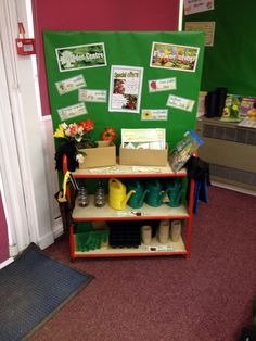 there is a green wall with pictures on it and some gardening equipment in front of the shelf