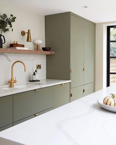 a white counter top in a kitchen next to a sink and window with plants on it