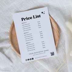 a price list sitting on top of a wooden plate next to dry grass and flowers