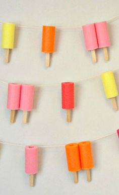 popsicles are lined up on a string with colored paper and toothpicks attached to them