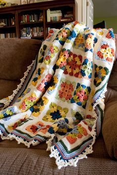 a crocheted granny's afghan on a couch with a bookcase in the background