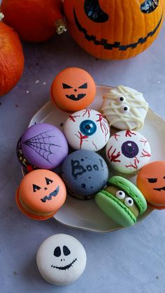 halloween decorated cookies on a plate next to pumpkins