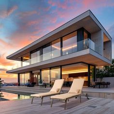 two lounge chairs sitting on top of a wooden deck next to a large swimming pool