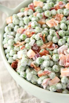 a bowl filled with peas and bacon on top of a table