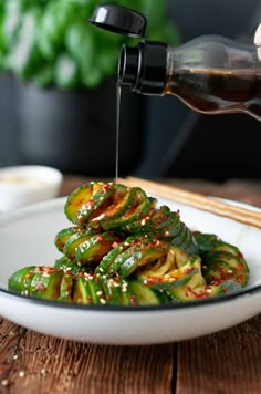 someone is pouring sauce on some green vegetables