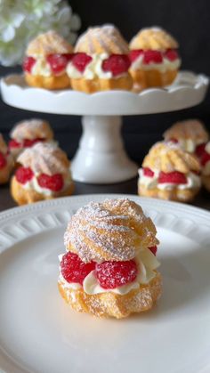 small pastries with strawberries and powdered sugar sit on white plates next to flowers