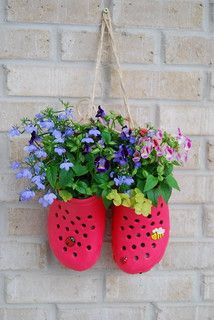 two red flower pots hanging on a brick wall with flowers in them and blue pansies