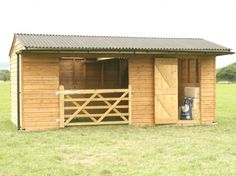 a horse stable with the doors open in a field