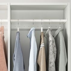 an open closet with clothes hanging on the rails and folded shirts in front of it