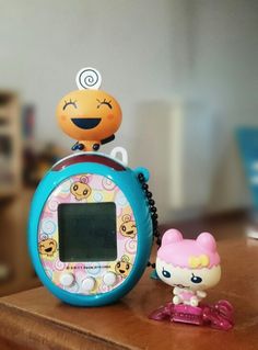 an alarm clock sitting on top of a wooden table next to a small toy cat