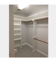 an empty walk in closet with white shelves