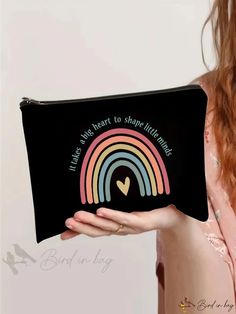 a woman is holding a black pouch with a rainbow on it