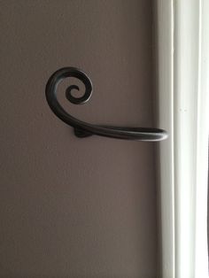 an iron door handle on the side of a white wall in front of a window