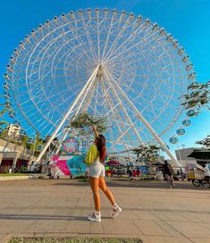 a woman standing in front of a large ferris wheel