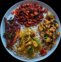 a white plate topped with rice and meat covered in sauce next to other food items