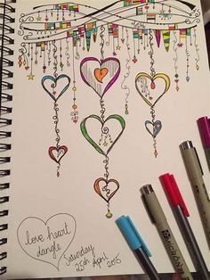 an open notebook with hearts hanging from it's strings and writing on the page