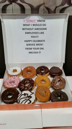 an open box filled with donuts sitting on top of a table next to a sign