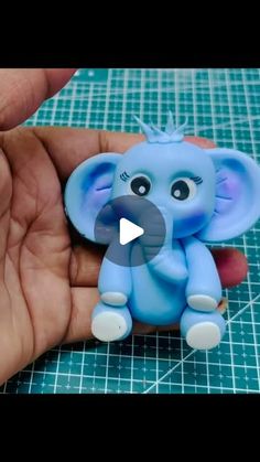 someone is holding a small blue elephant in their hand