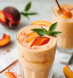 two glasses filled with peach milkshakes on top of a table