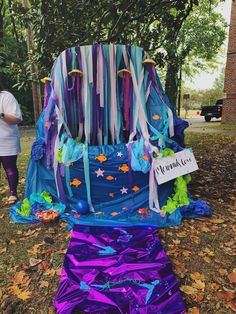 a purple and blue chair sitting on top of a grass covered field next to trees