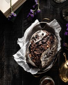 a loaf of bread sitting on top of a wooden table next to some purple flowers