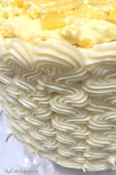 a close up of a cake with white frosting and yellow icing on it