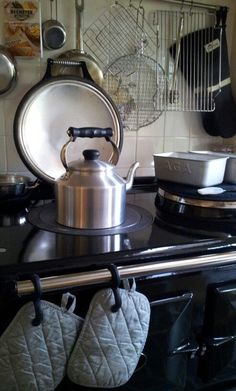 a tea kettle sitting on top of a stove with pots and pans hanging above it