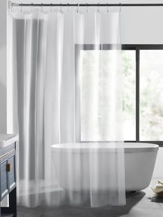 a white bath tub sitting next to a window in a bathroom with black and white decor