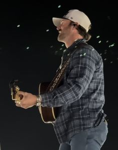 a man holding a guitar and wearing a hat