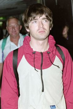 a young man wearing a red and white jacket is standing in front of other people